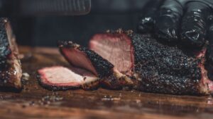 Primer plano de un corte de carne ahumada mostrando el anillo de humo rosa y la costra exterior.⁠