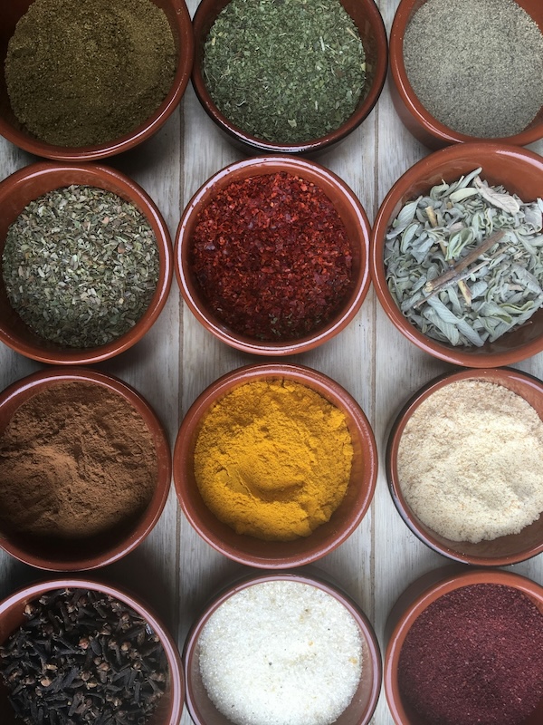 Varios cuencos pequeños de cocina con pimentón, azúcar moreno, sal y pimienta gorda y otros.